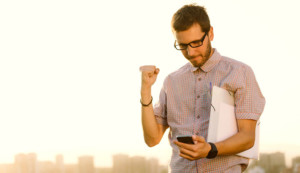 Person holding their fist up in success while looking at phone