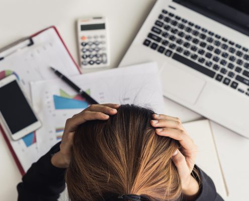 Person with hands on head stressing over data on paper