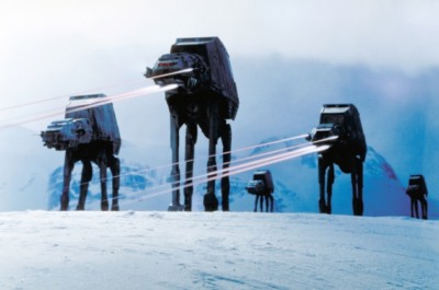 Tall Machines With Lasers coming out of them on Snow with mountains behind