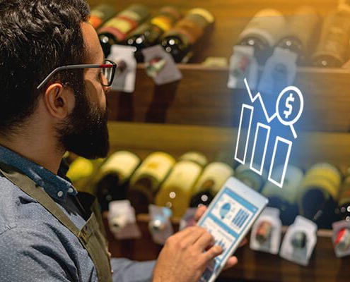 Person holding ipad with heads up display in front of shelves of wine bottles
