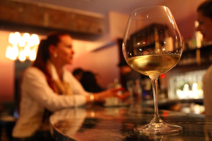 White wine in glass in front of woman at bar(blurred background)