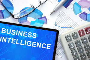 Business Intelligence on Notepad with Calculator, glasses, and paper next to it