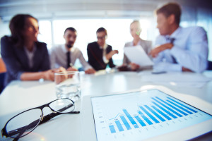 notepad and glasses on table in front of people in meeting